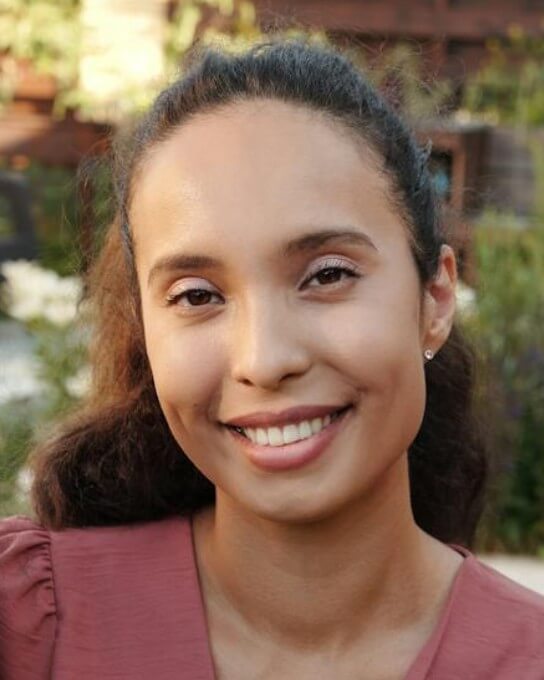 a female with curly hair in the pink blouse