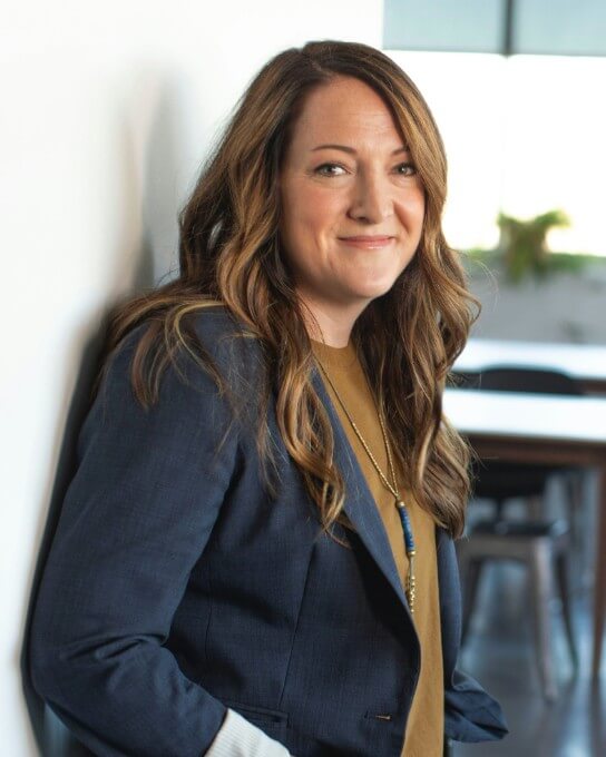 a woman in dark blue coat leaning on the white wall