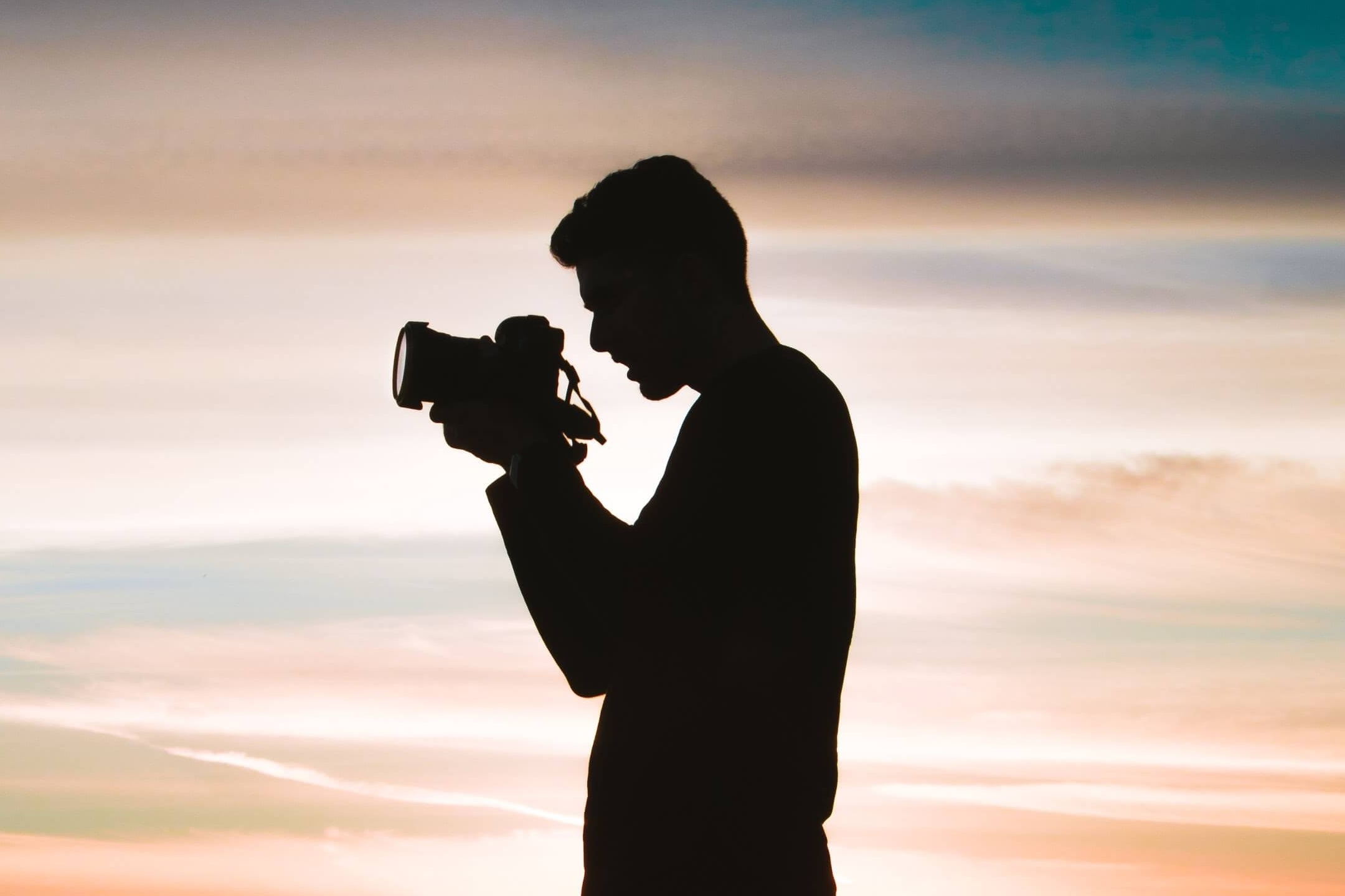 A shadow of a boy carrying the camera with red sky behind