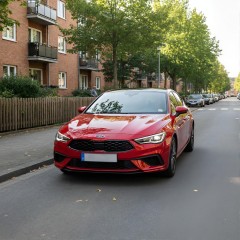 A red car in the parking lot of a residence thumbnail
