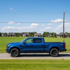 A small blue truck on a town road thumbnail