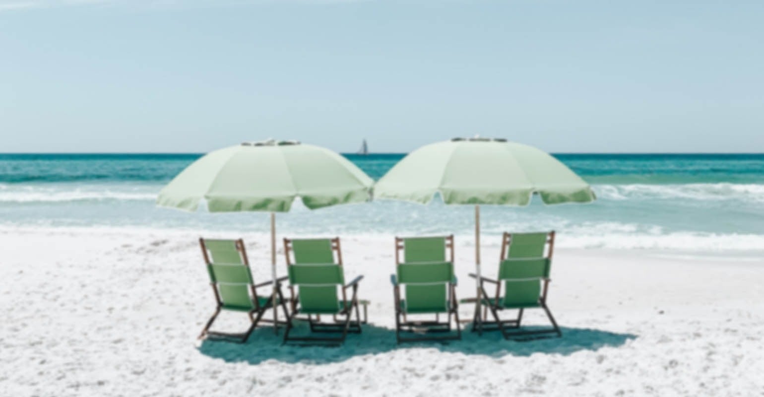 Ein unscharfes Foto von grünen Stühlen unter Sonnenschirmen am Strand