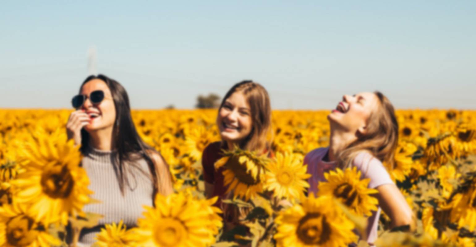 Una piccola foto sfocata di tre donne in piedi in un campo di girasoli