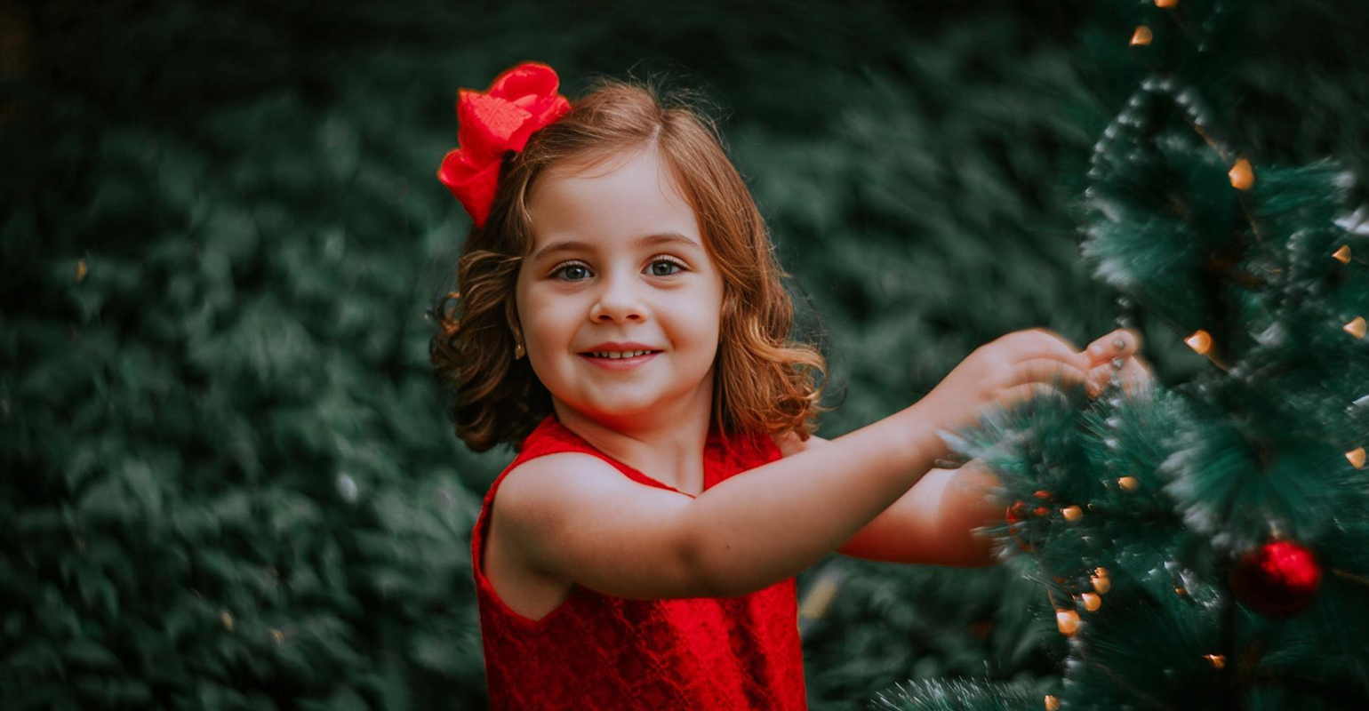 Bambina in piedi accanto all'albero di Natale
